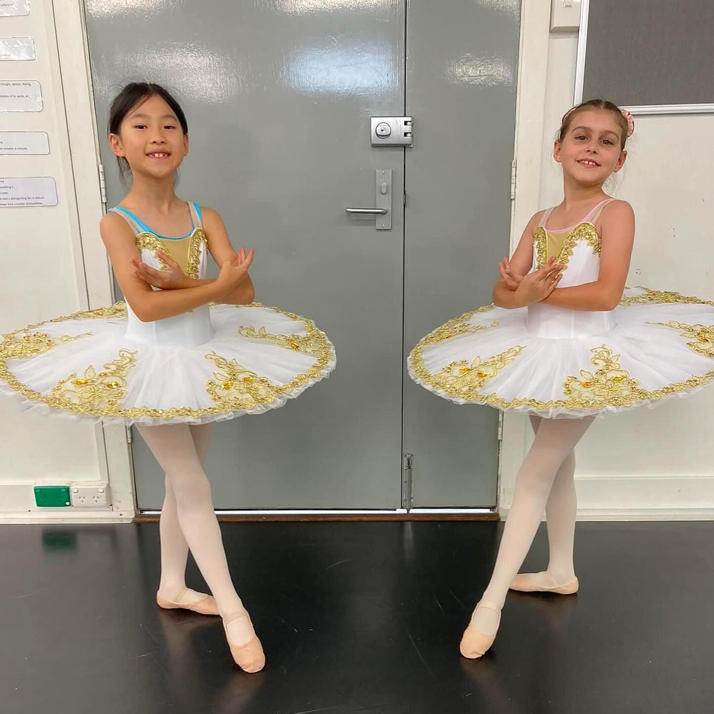 Two Young Ballet Dancers in White Tutus With Gold Trim, Arms Crossed — Kay Flynn Dancing Academy Southport in Southport, QLD