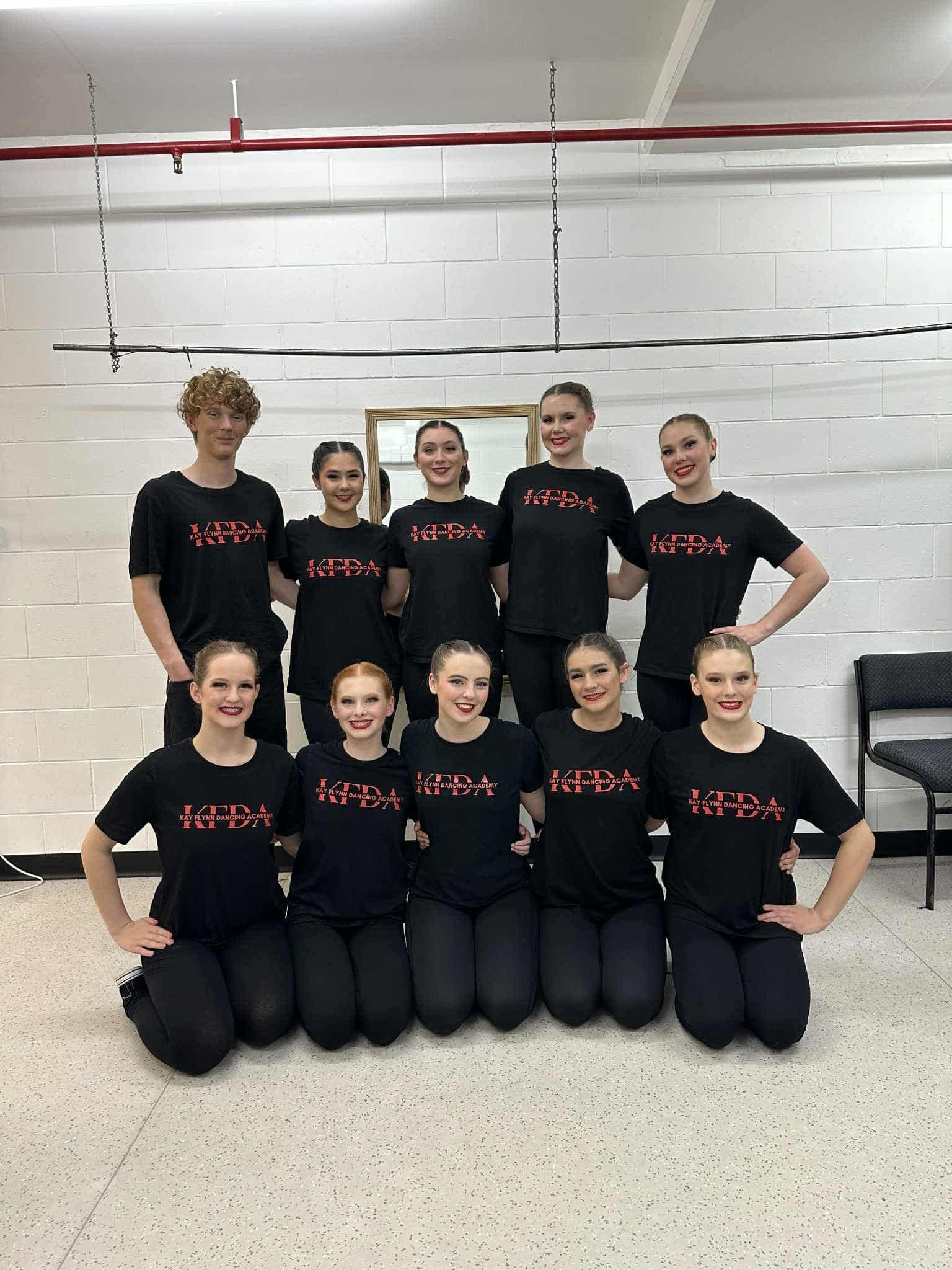 Group of Dancers in Black Shirts and Pants Posing in a Dance Studio — Kay Flynn Dancing Academy Southport in Southport, QLD