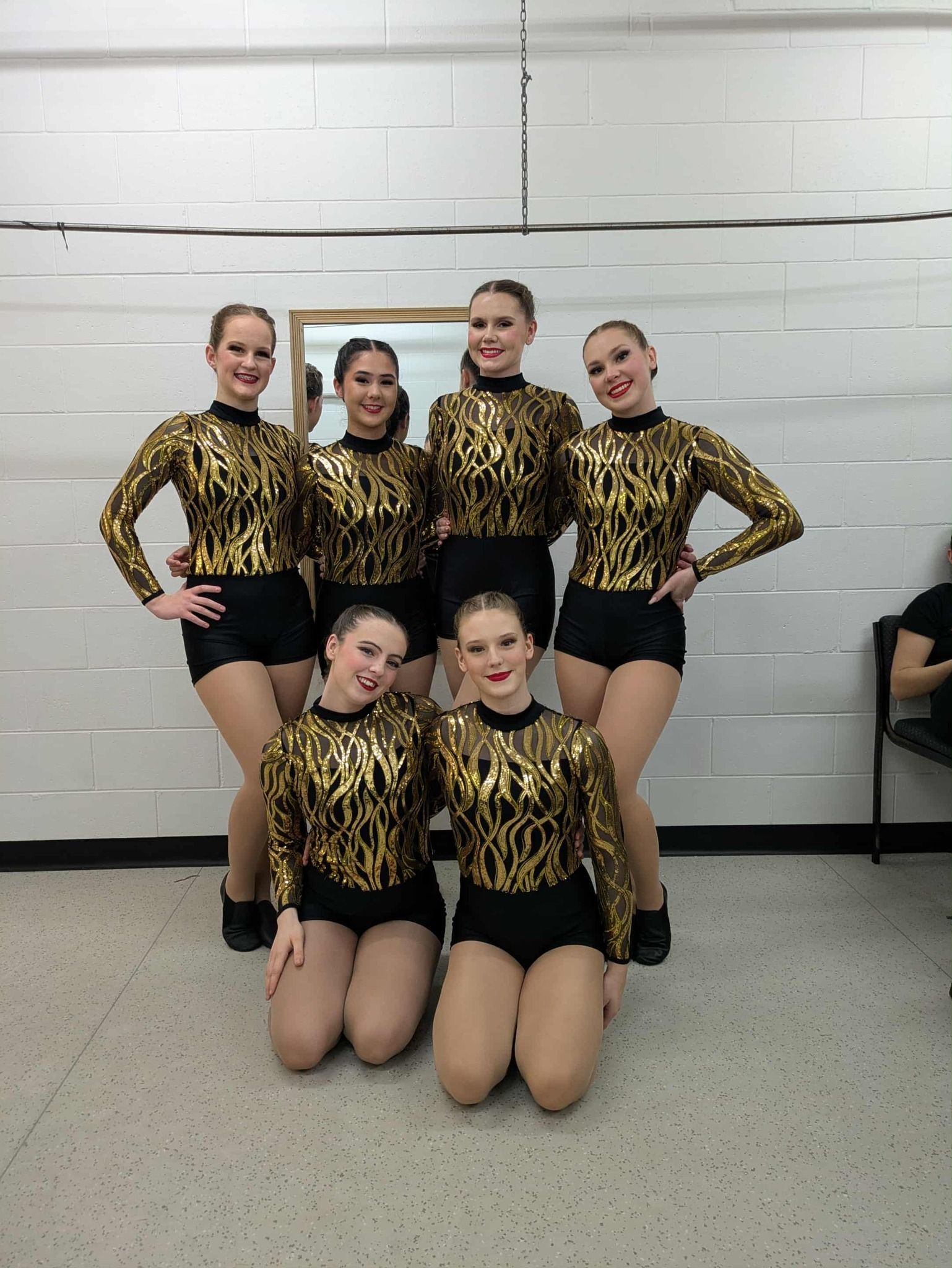 A Dance Team of Six Girls in Gold and Black Outfits Poses in a Studio — Kay Flynn Dancing Academy Southport in Southport, QLD