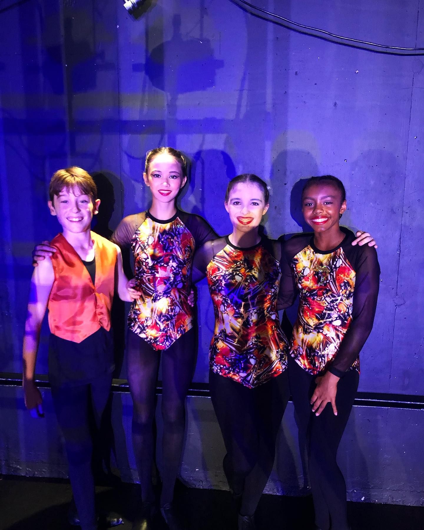 Four Young Dancers in Costumes Pose on Stage, Lit With Blue Light — Kay Flynn Dancing Academy Southport in Southport, QLD