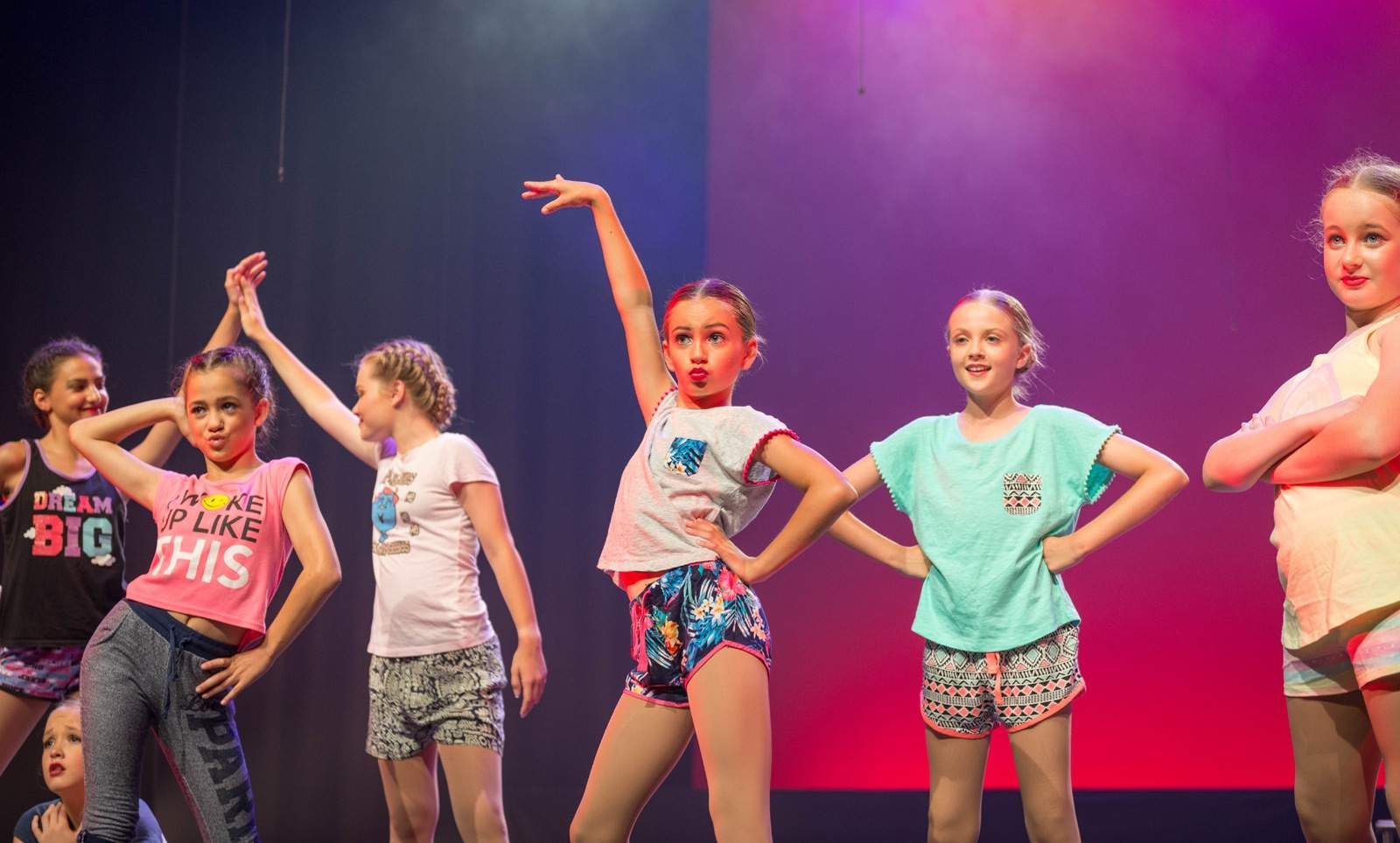 A Group of Young Dancers Performing on Stage With Arms Raised — Kay Flynn Dancing Academy Southport in Southport, QLD