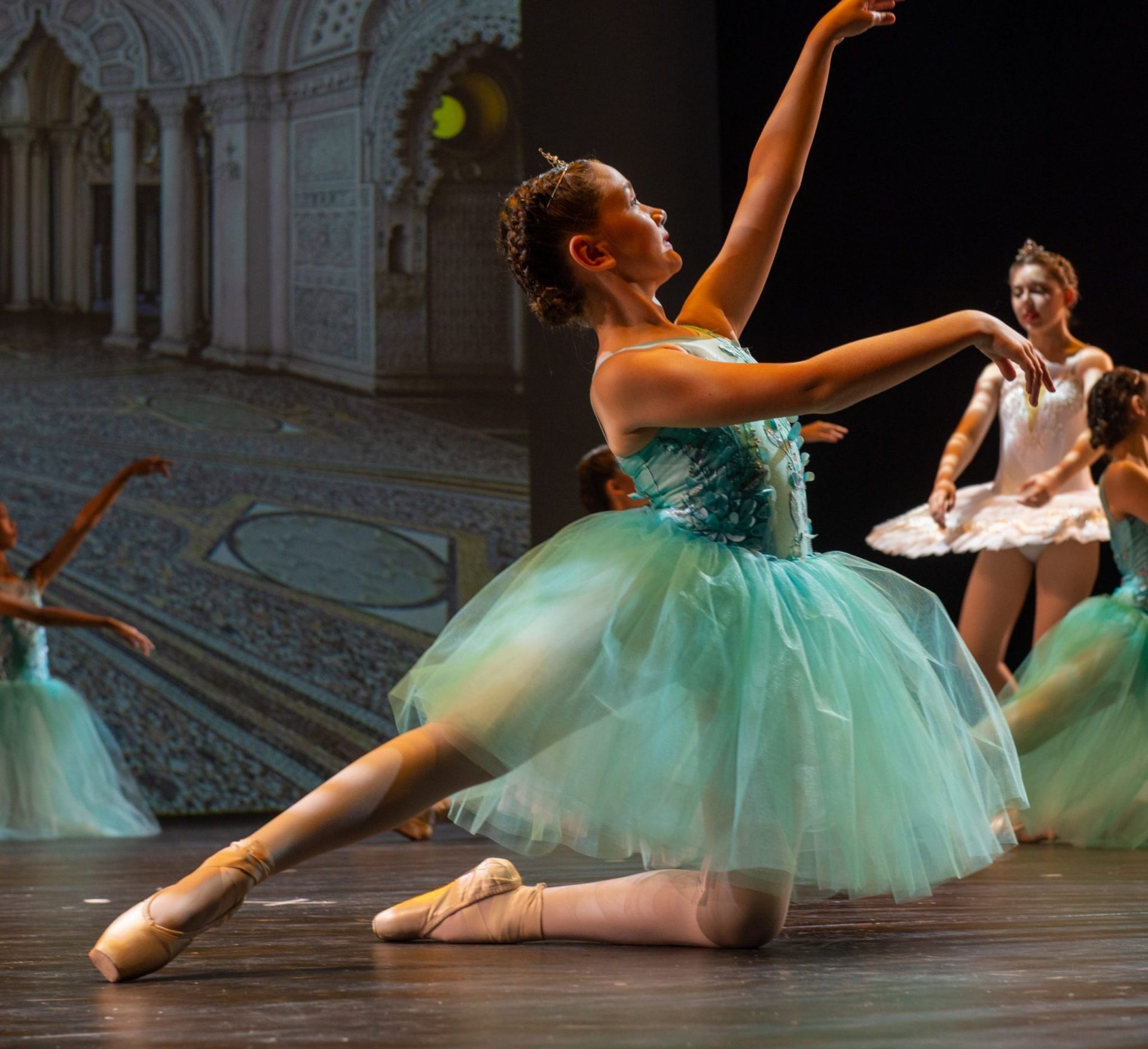 Ballet Dancer in Teal Tutu, Kneeling With Arms Extended, on Stage — Kay Flynn Dancing Academy Southport in Southport, QLD