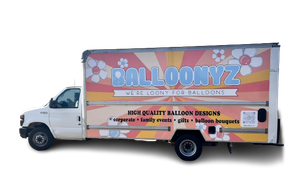 White delivery truck with BALLOONYZ branding, floral graphics, and text advertising balloon designs. White delivery truck with BALLOONYZ branding, floral graphics, and text advertising balloon designs.