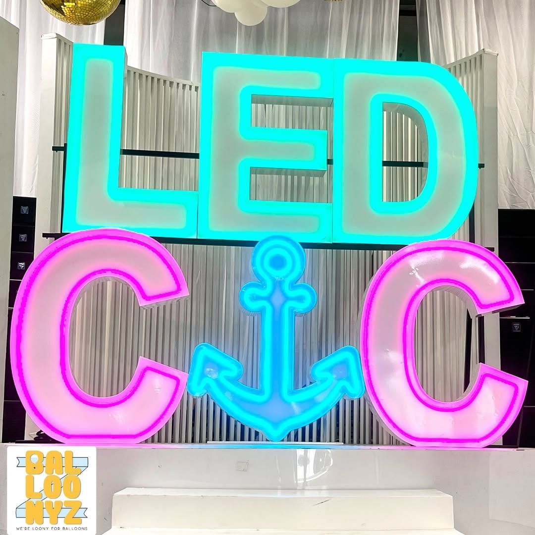 Woman on red couch under rainbow balloon arch with painted background.