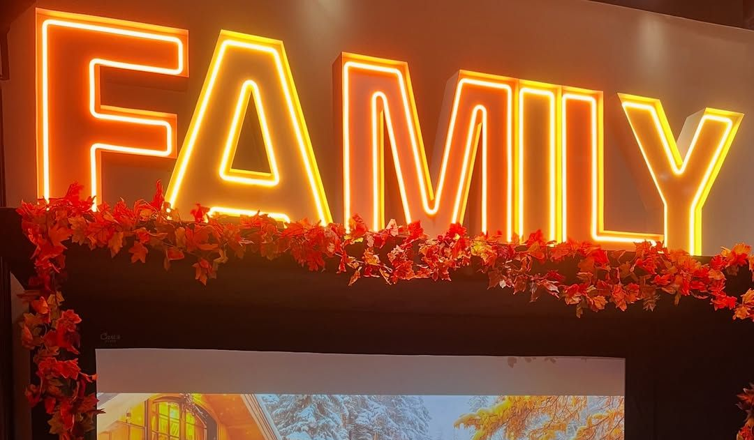Pregnant woman in beige dress at a party with a balloon arch.