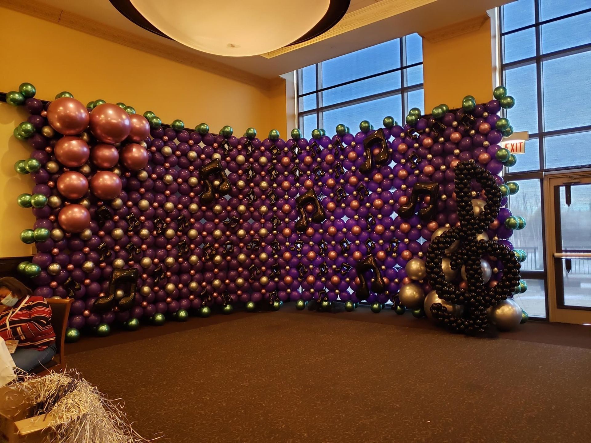 Purple and black balloon wall with accents of green and gold, for an event.
