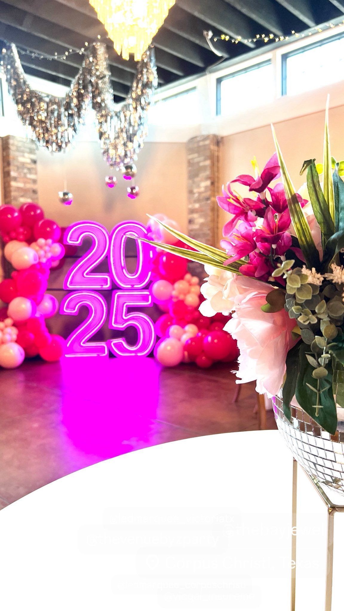 Bright party scene with pink balloons, 2025 sign, and floral arrangement.