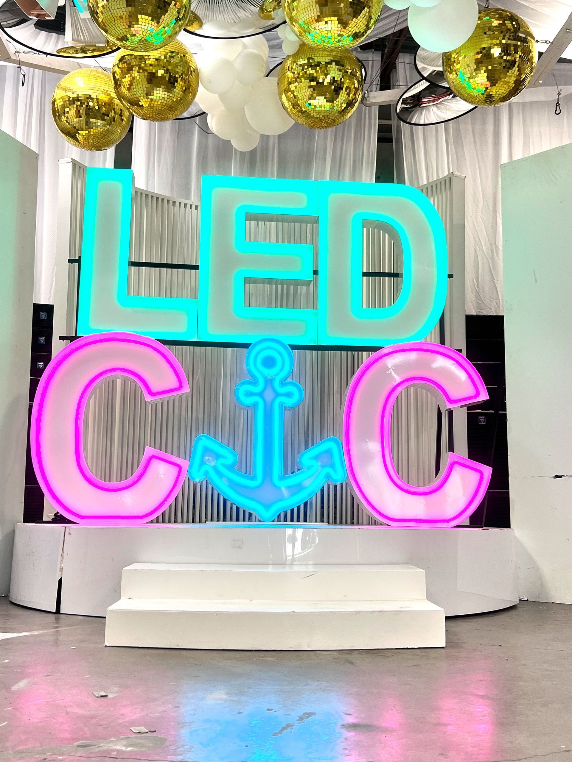 LED C & C sign with anchor, stage, gold and white decor.