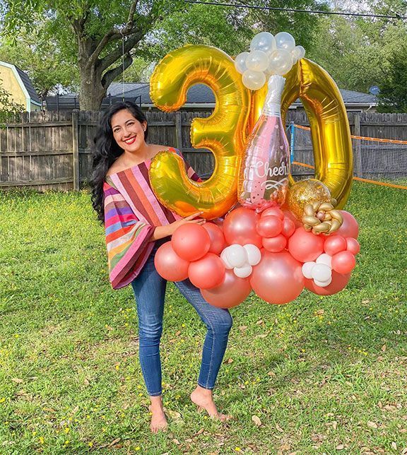 Woman holding a balloon arrangement with gold 