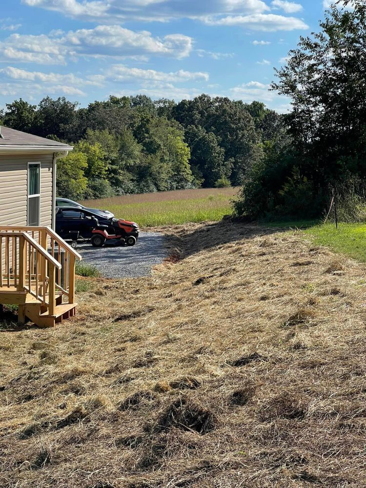 A house is sitting on top of a grassy hill next to a field.