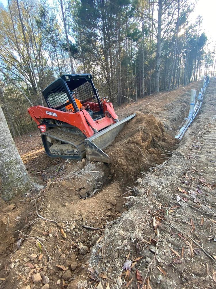 A bulldozer is digging a hole in the dirt in the woods.