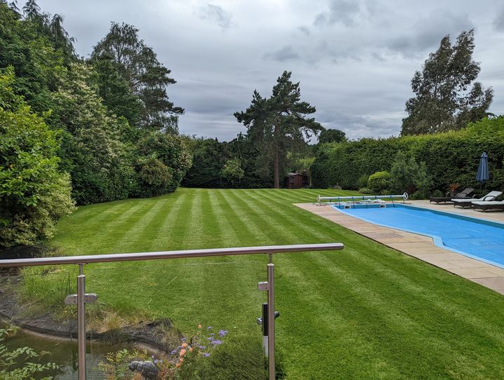 Lawn with mower stripes and large swimming pool