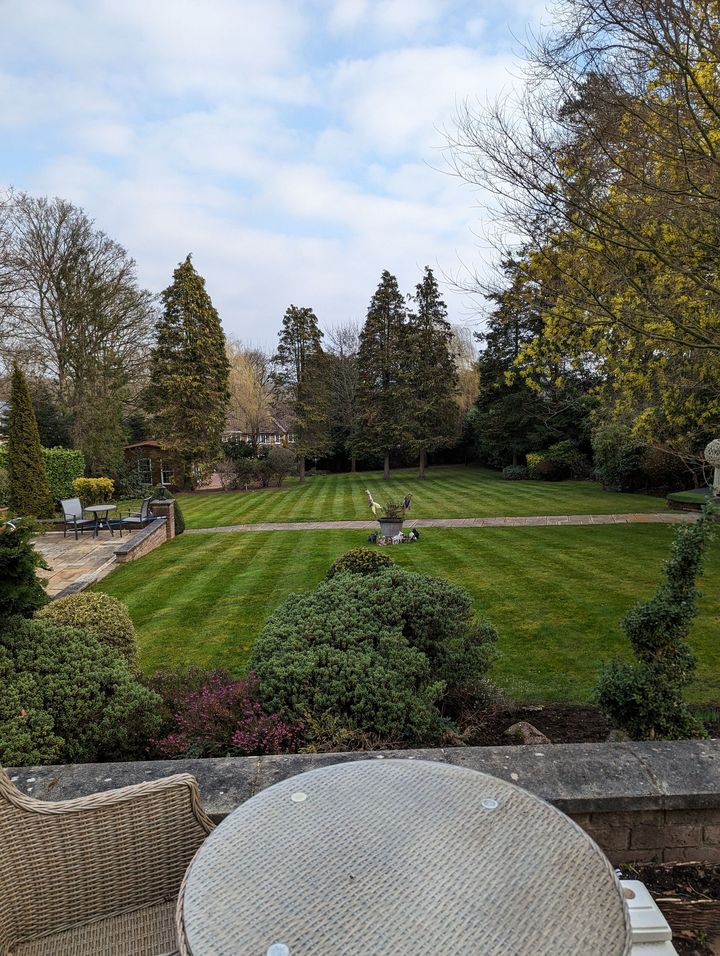 Large garden with patio, seating area and tall trees