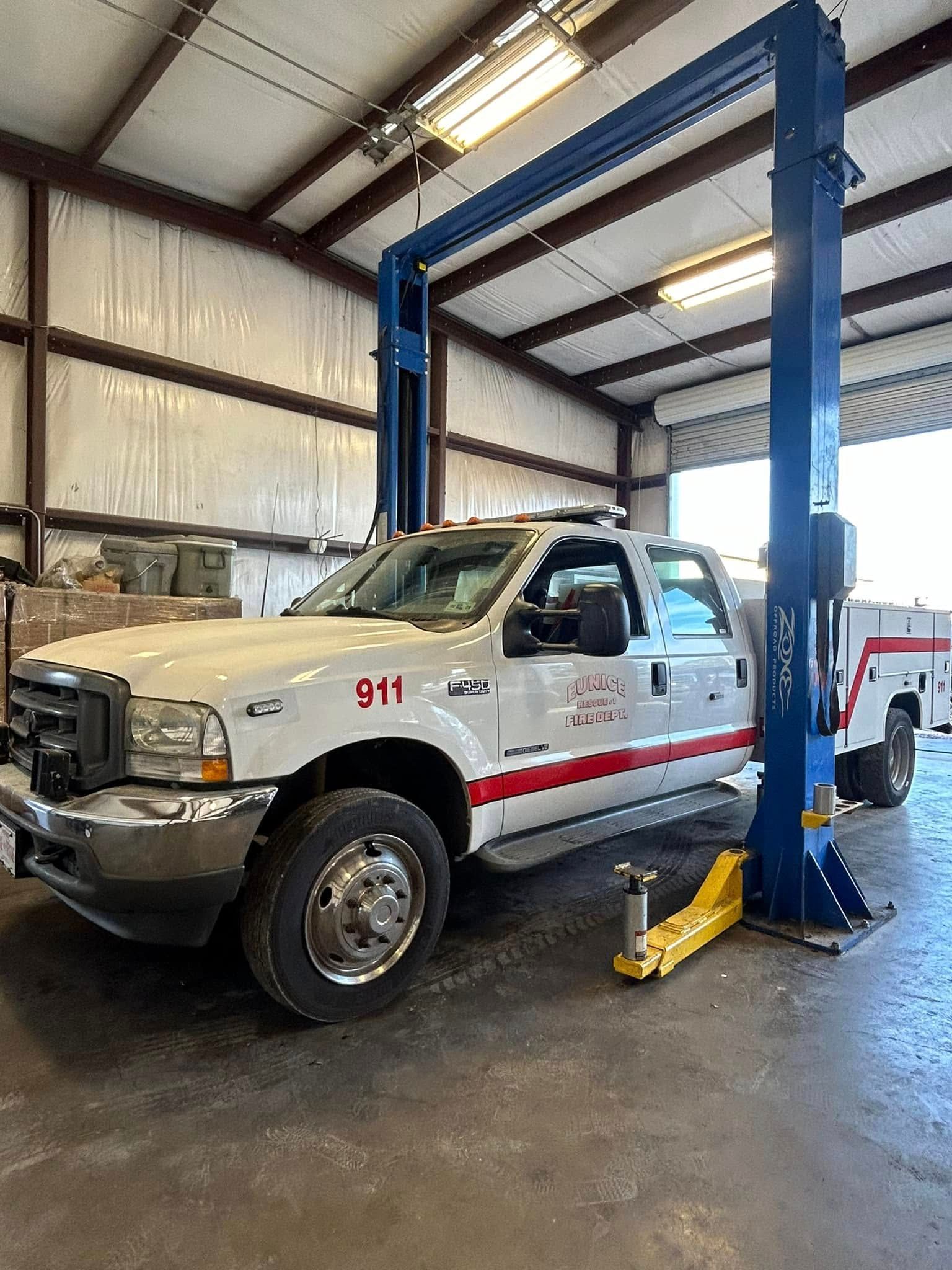 A white truck is parked on a lift in a garage.
