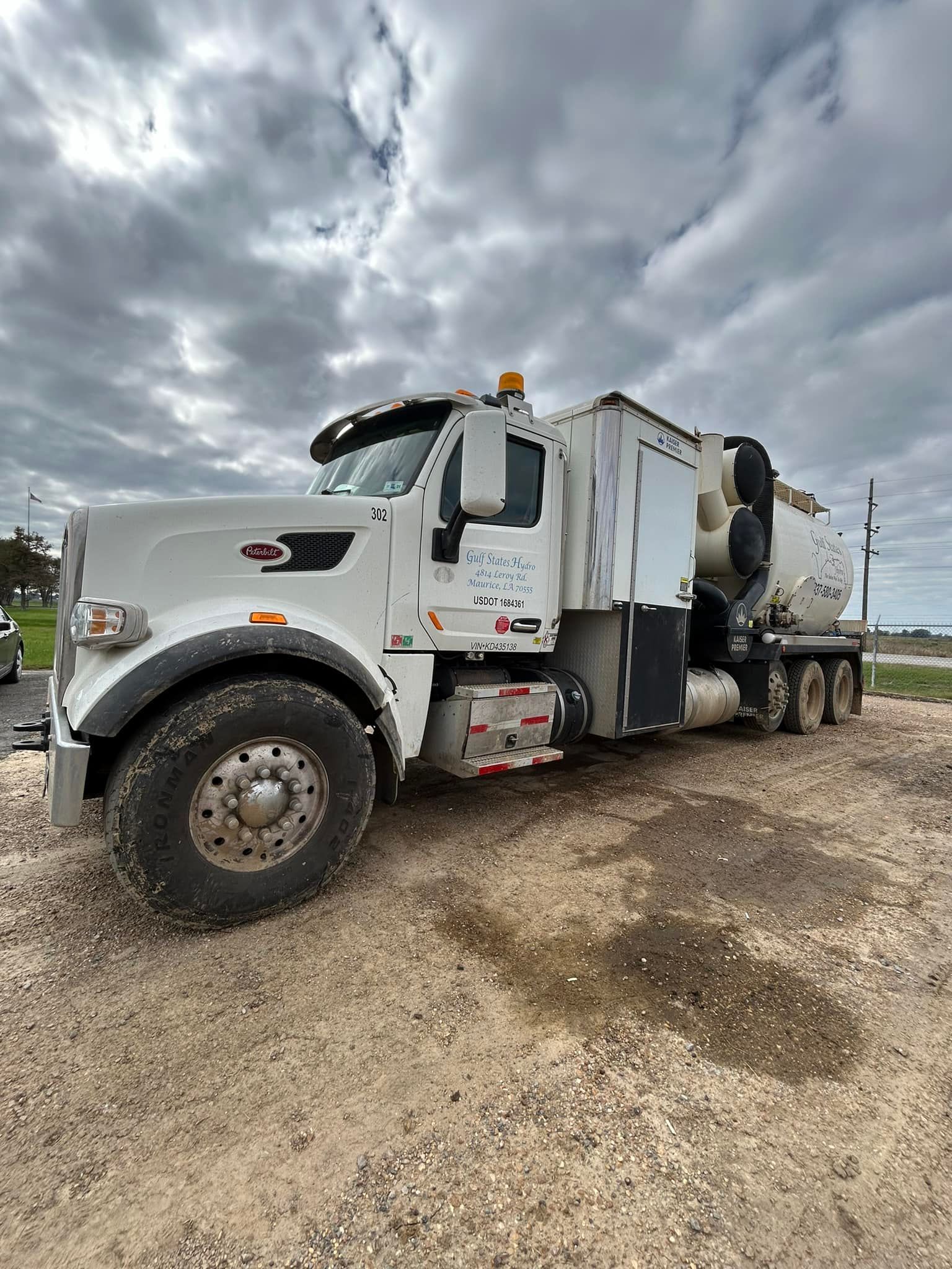 A large white truck is parked in a dirt field.