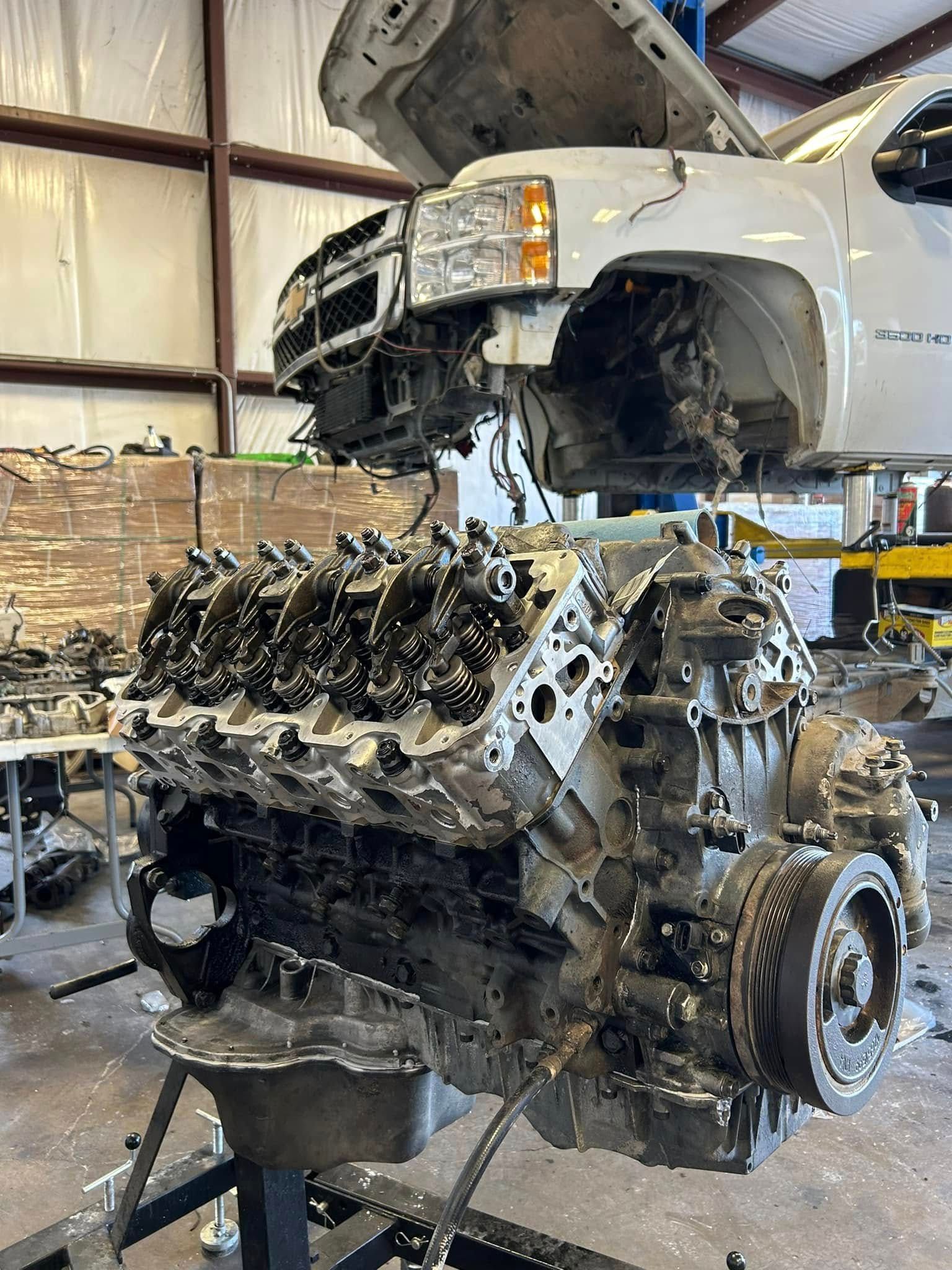 A large engine is being removed from a truck in a garage.