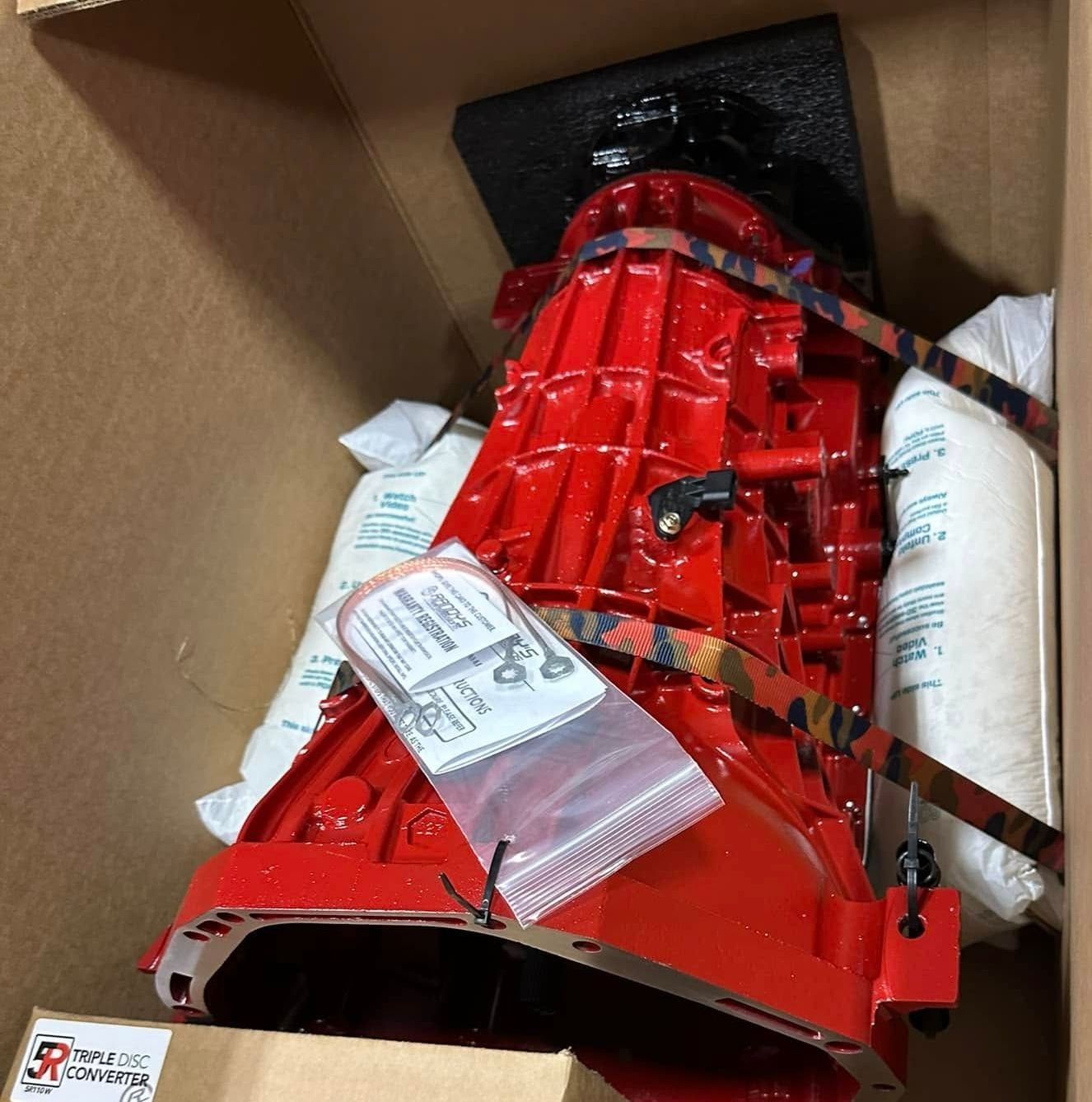 A red engine is sitting in a cardboard box