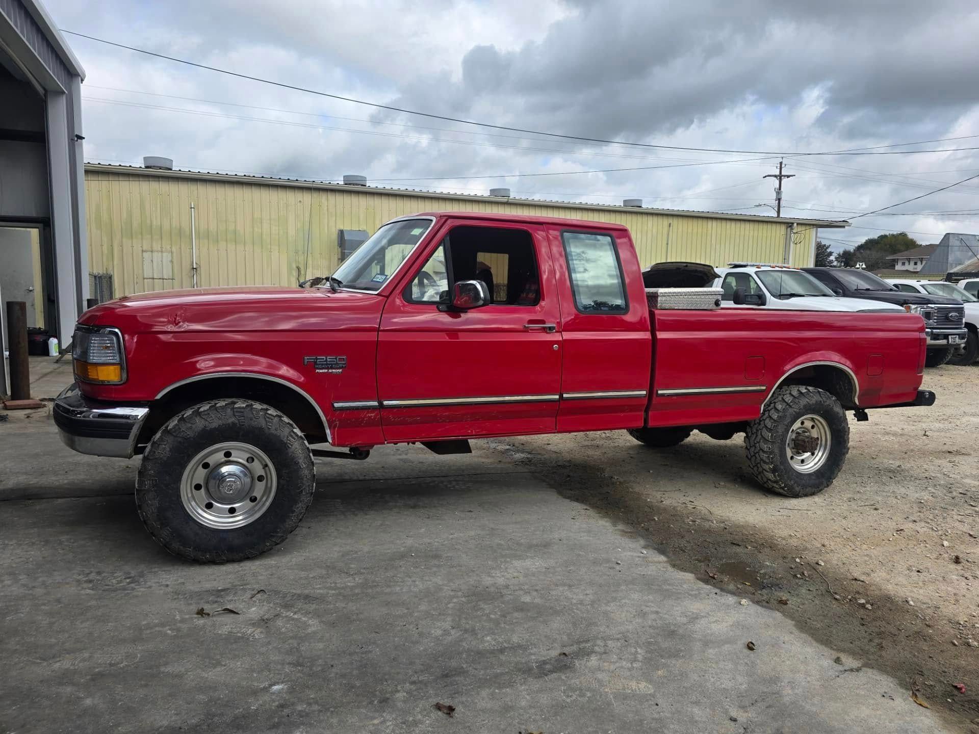 A red truck is parked in a parking lot in front of a building.