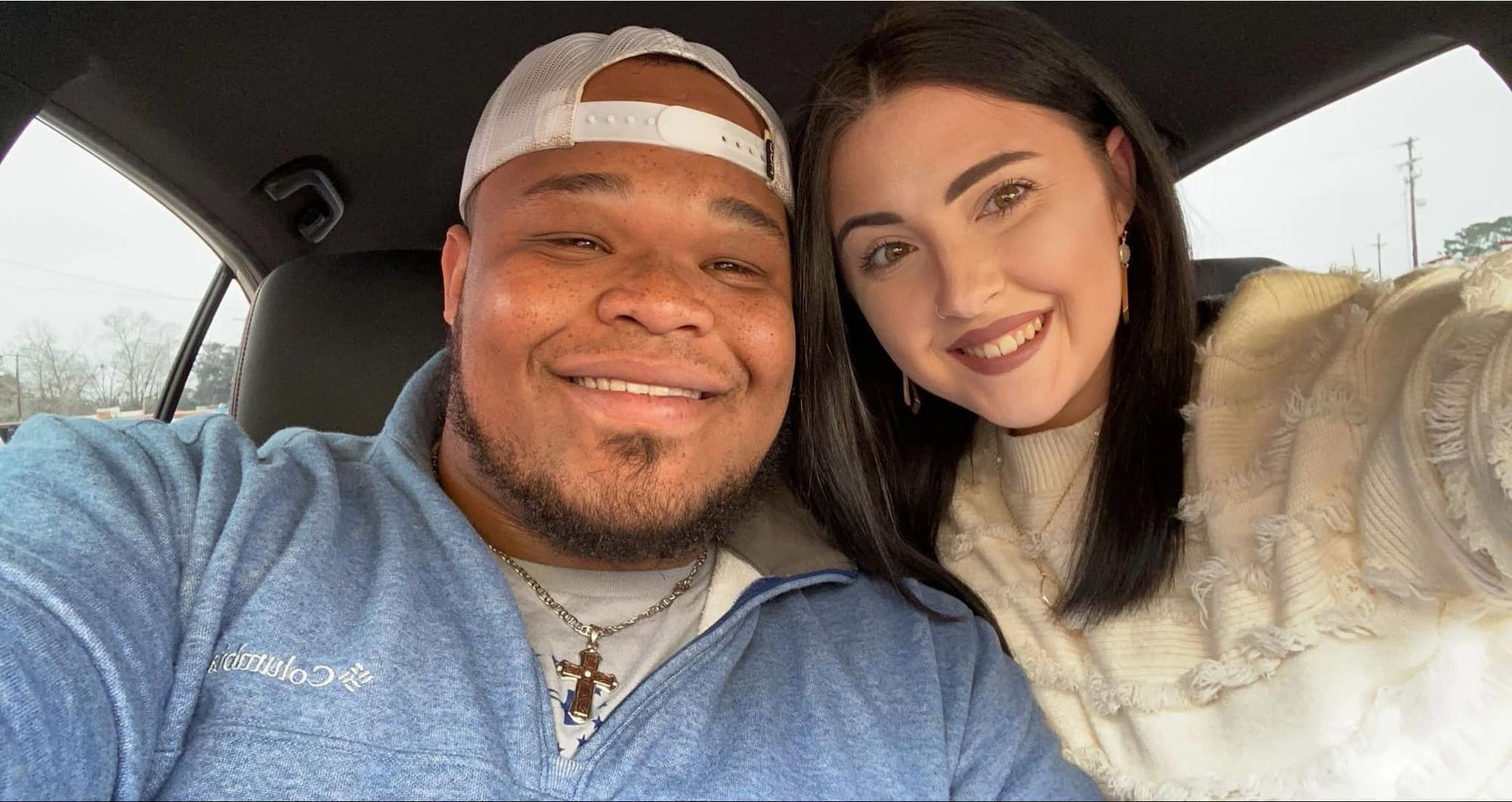 A man and a woman are taking a selfie in a car.