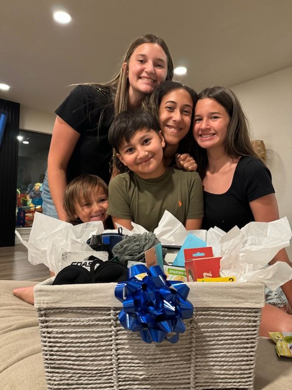 A group of children are posing for a picture in front of a basket filled with toys.