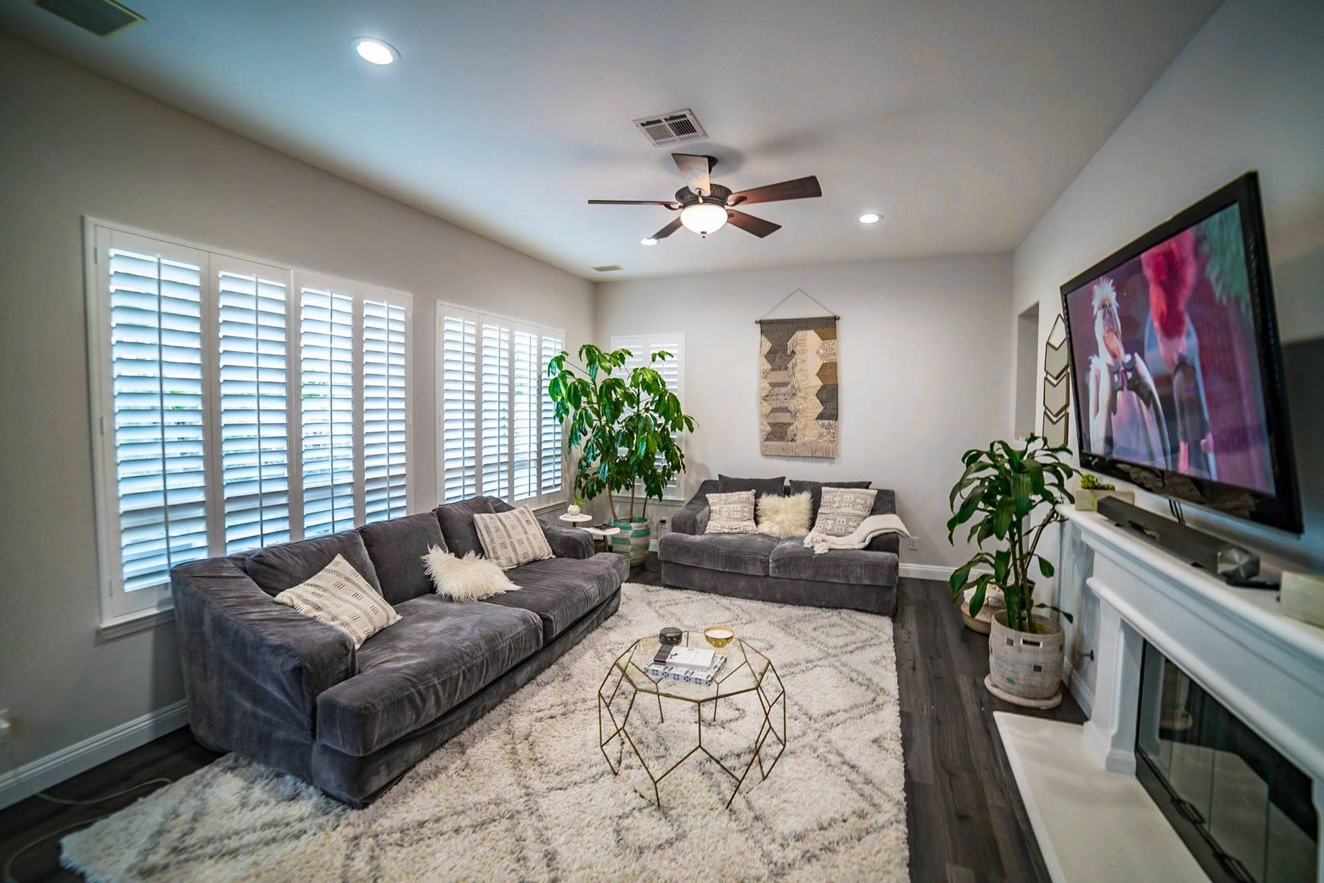 A living room with a couch , fireplace , television and ceiling fan.