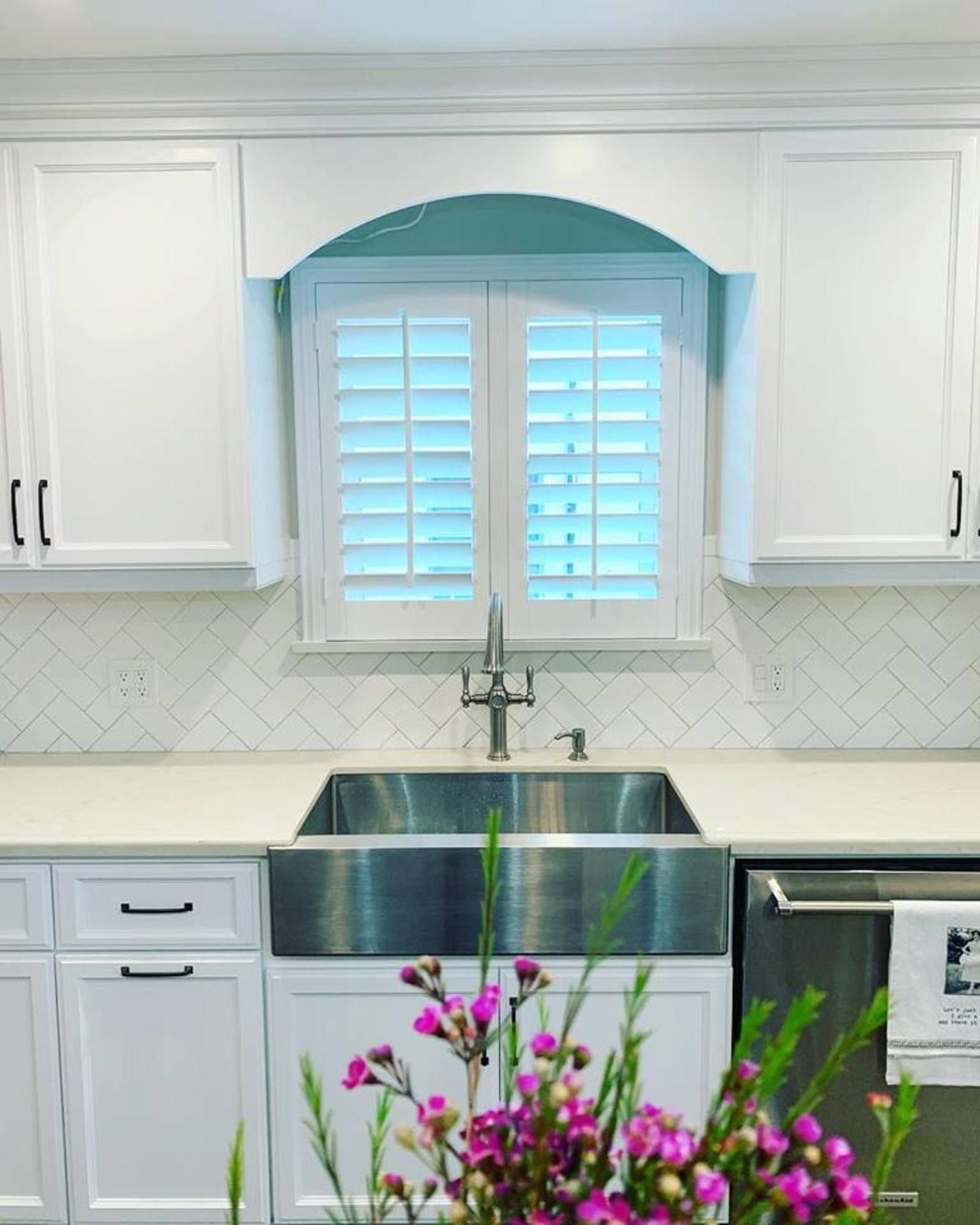 A kitchen with white cabinets and a stainless steel sink