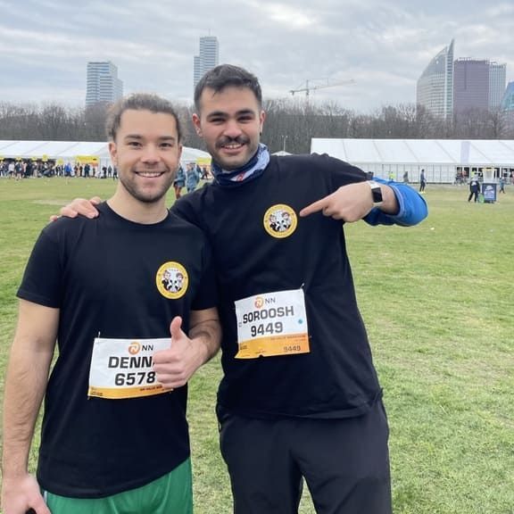 Two men posing for a picture with one wearing a shirt that says denn 6578