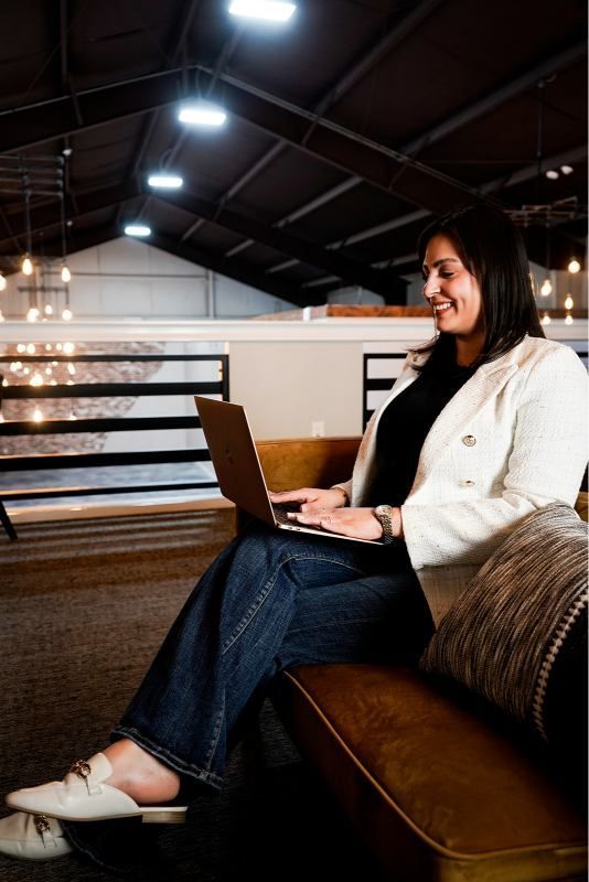 Woman working on a laptop while seated on a couch in a modern office lounge