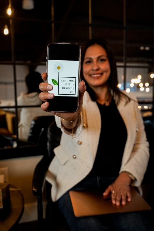 Woman smiling and holding up a smartphone in a dimly lit café