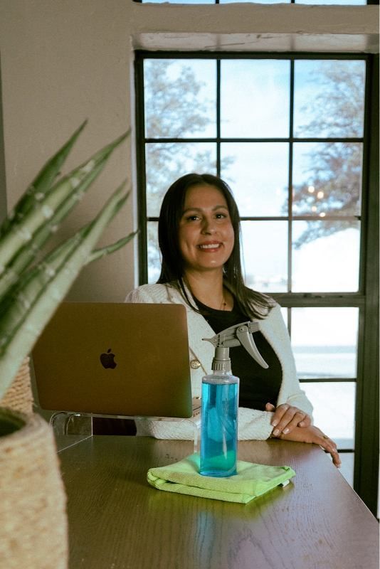 Woman standing by a laptop with a blue water bottle on a desk near a window
