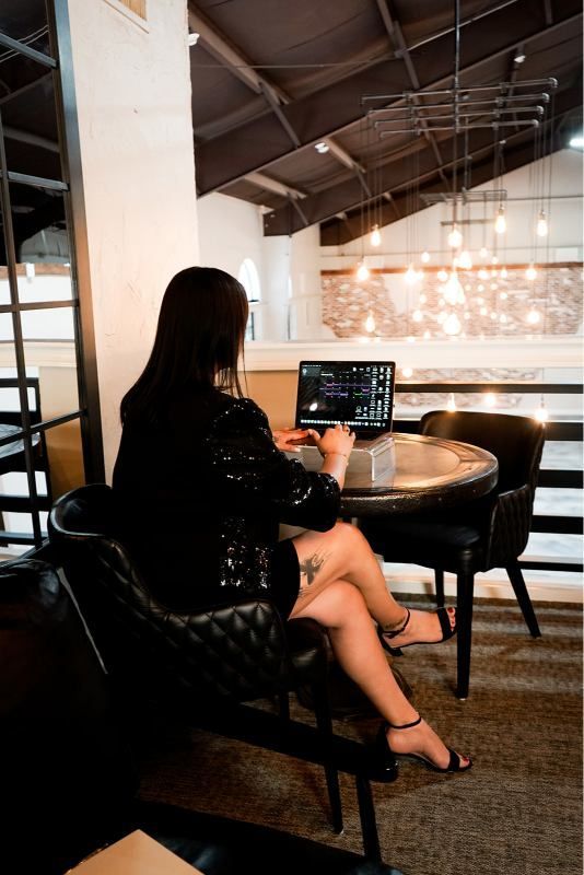 Person seated at a café table using a laptop, with warm lights and an industrial-style interior in the background.