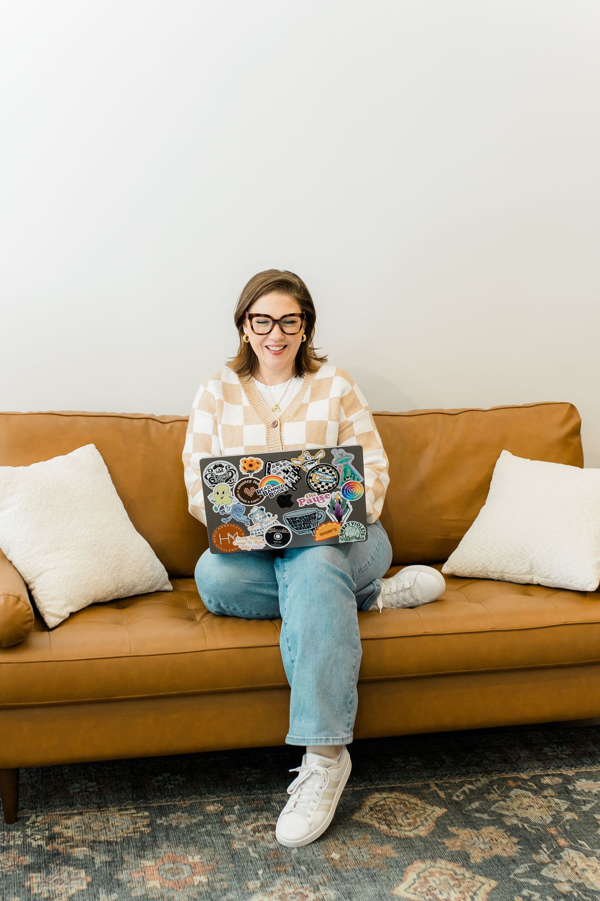 A woman is sitting on a couch holding a cup of coffee.