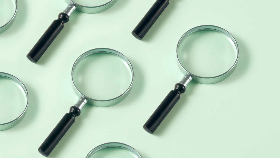 A group of magnifying glasses sitting on top of each other on a green surface.