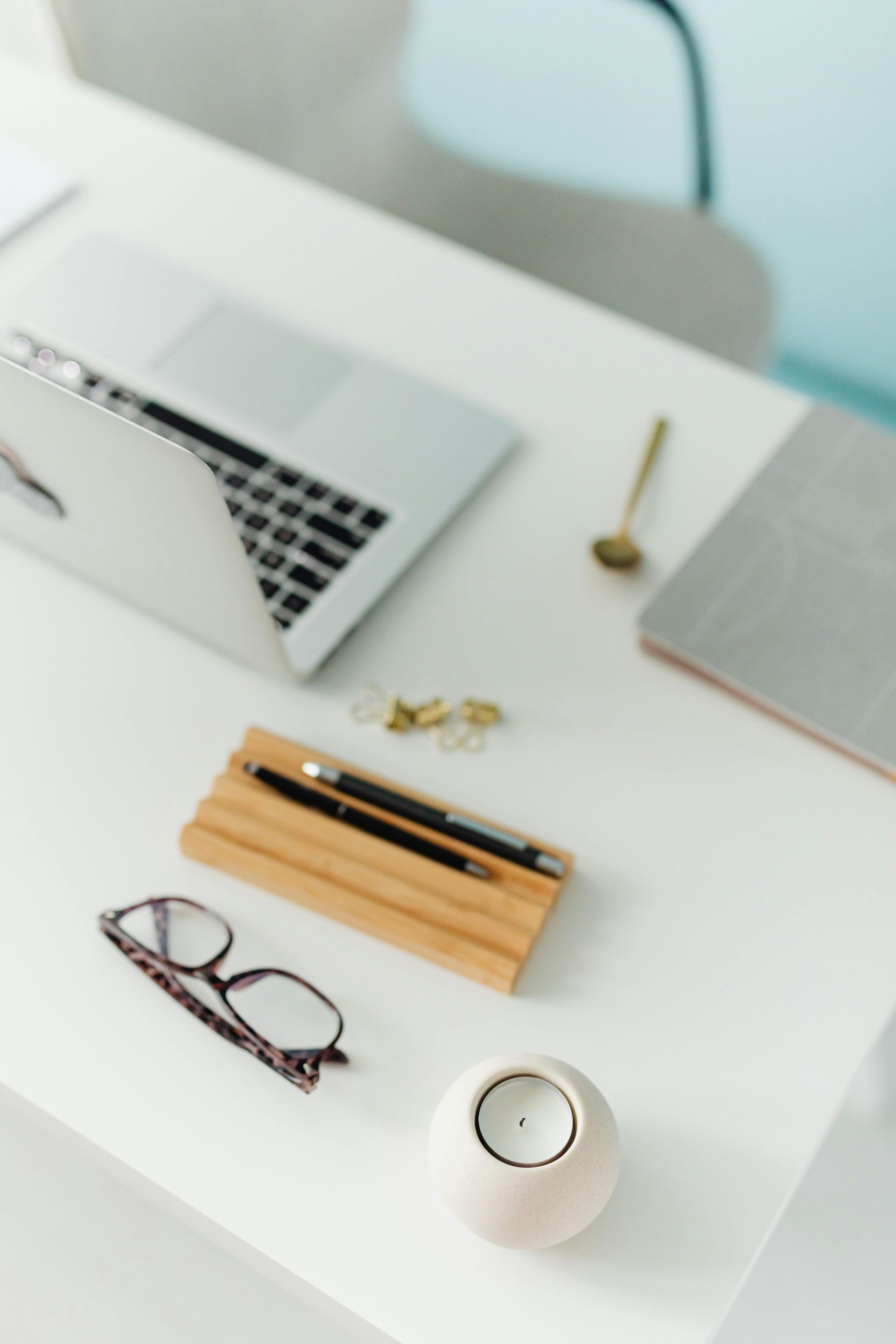 A white desk with a laptop and glasses on it