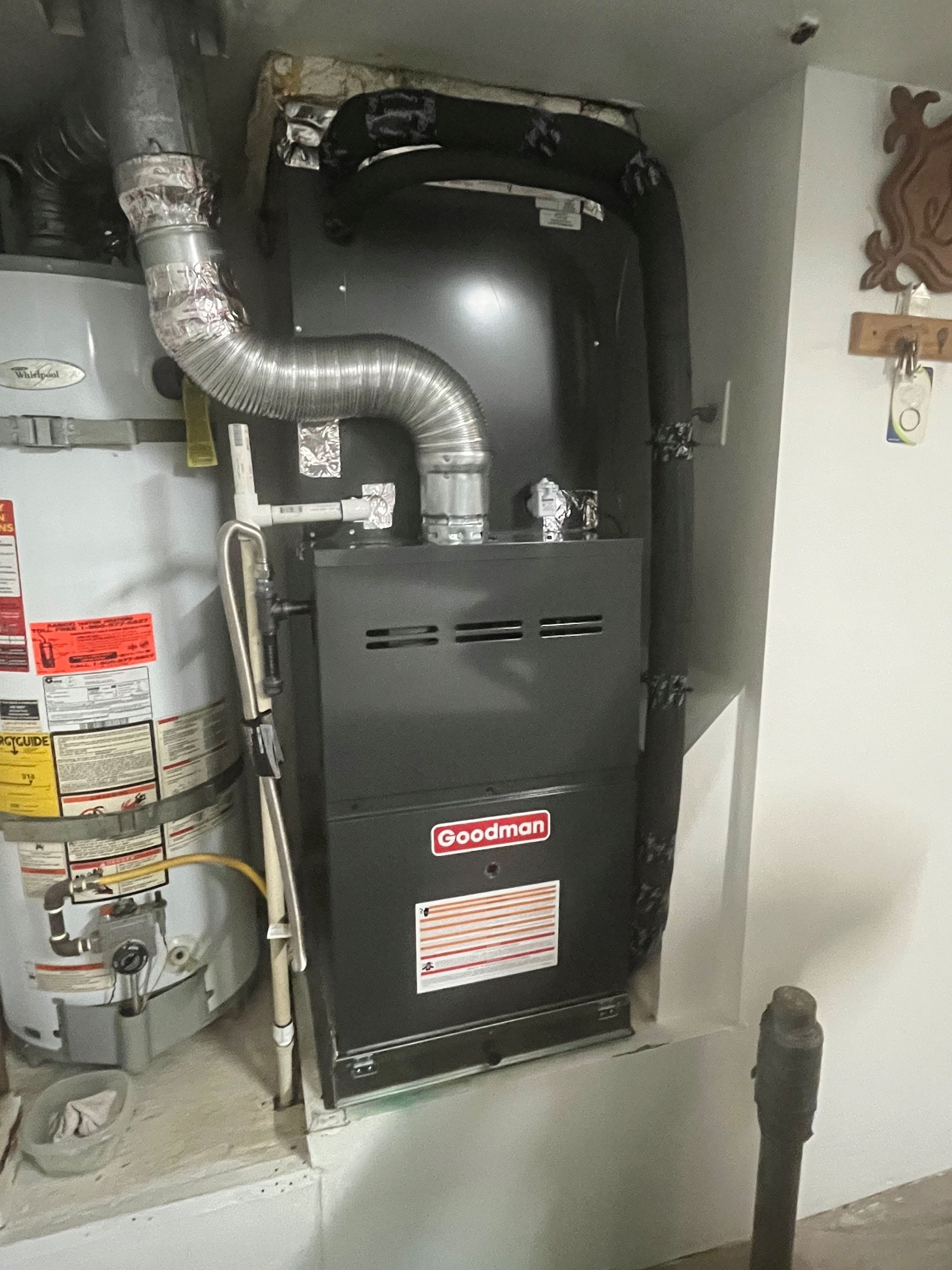 A gas heater is sitting next to a water heater in a basement.
