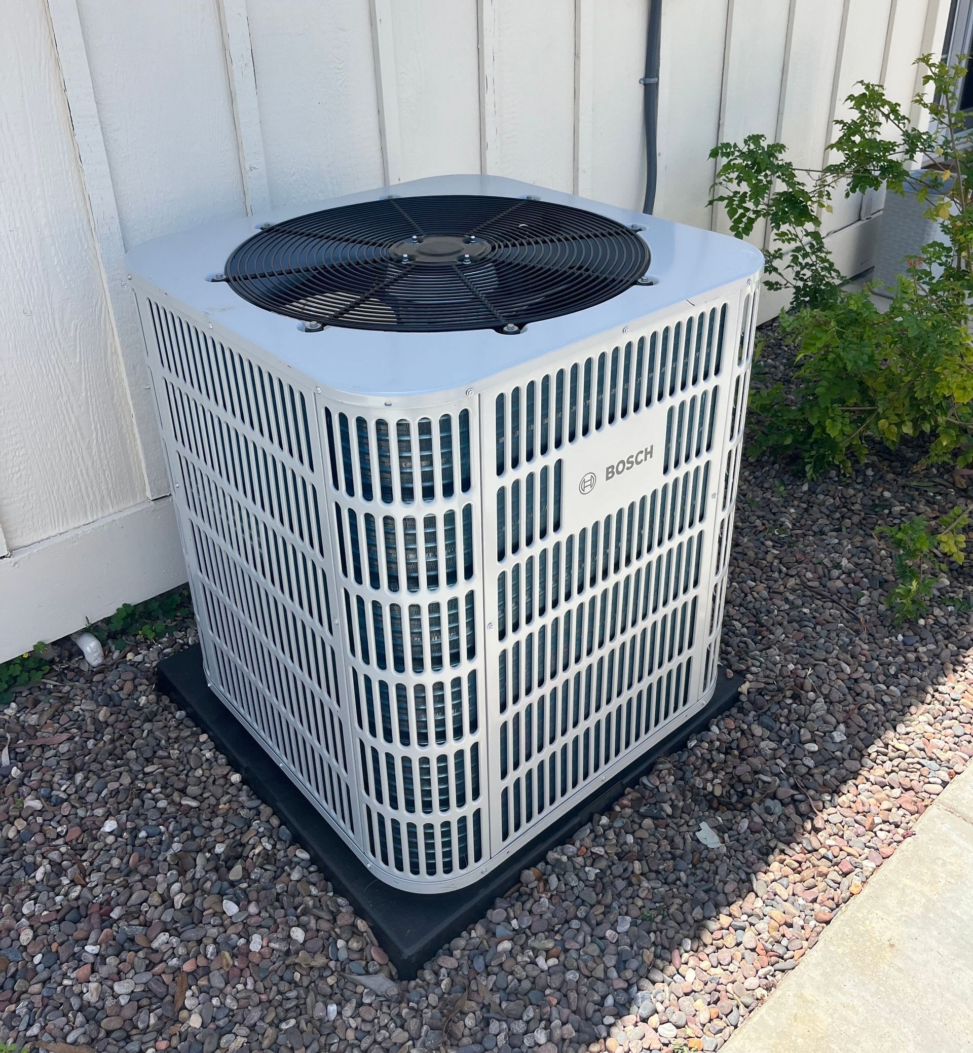 A man is standing next to an air conditioner holding a tool.