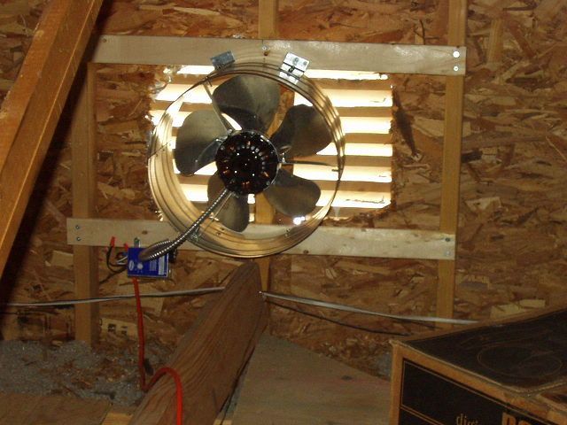 A fan is hanging from the ceiling of an attic