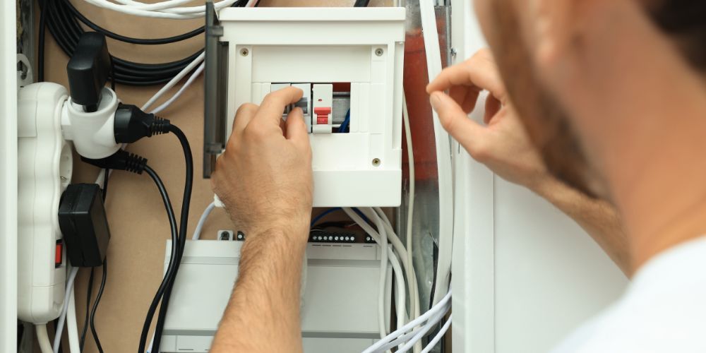 A man is working on an electrical box.