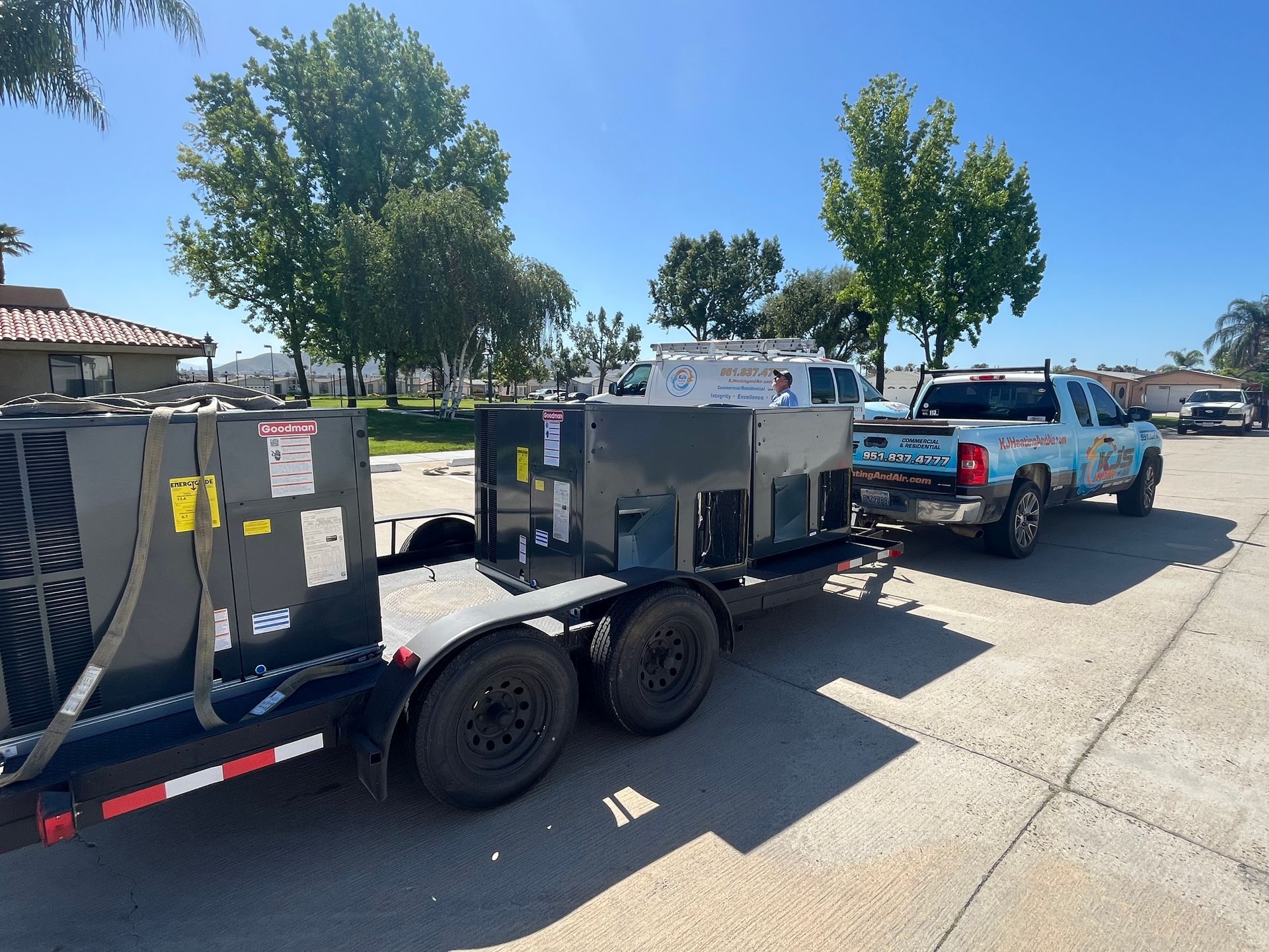 Truck towing a trailer with two large industrial generators on a sunny day.