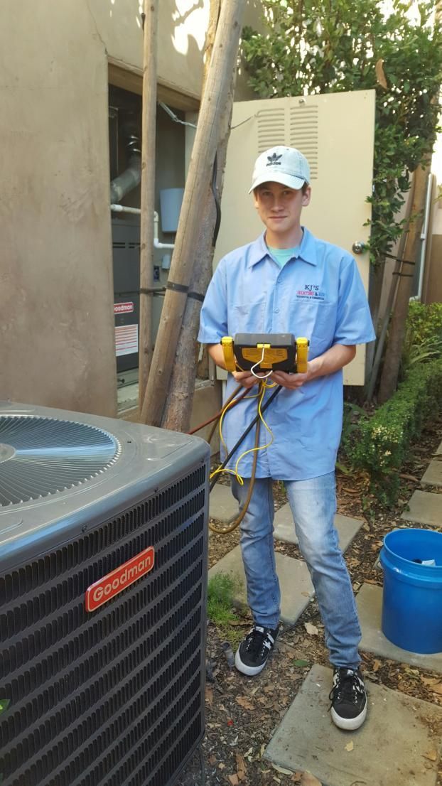 A man is standing next to an air conditioner holding a tool.