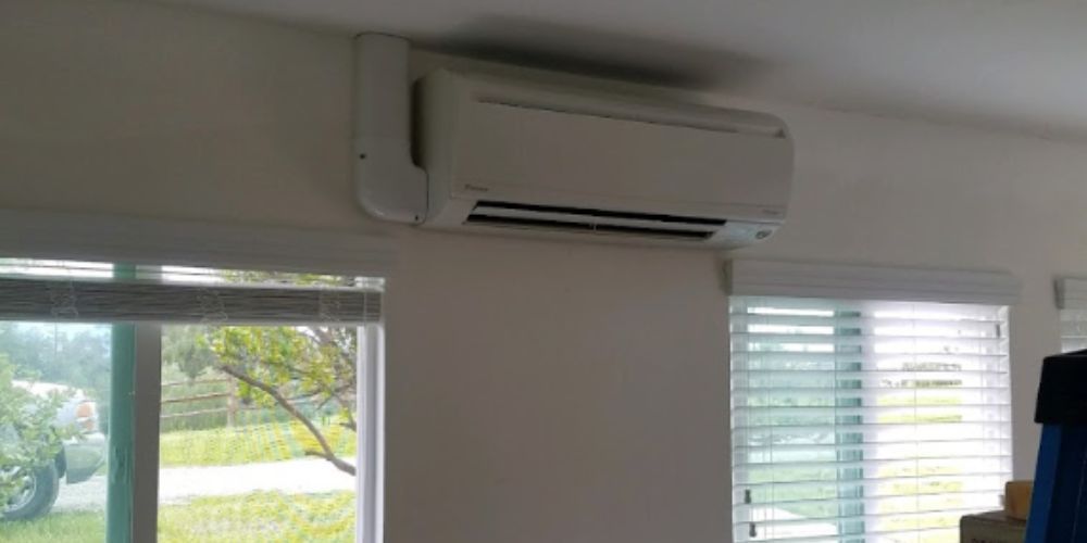 A room with a window and a wall mounted air conditioner.