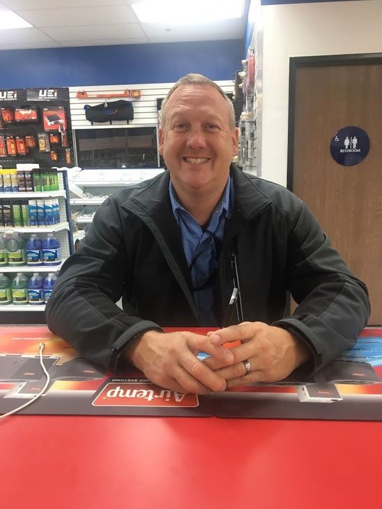 A man is sitting at a red table in a store.