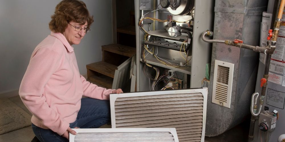 A woman is cleaning an air conditioner in a basement.