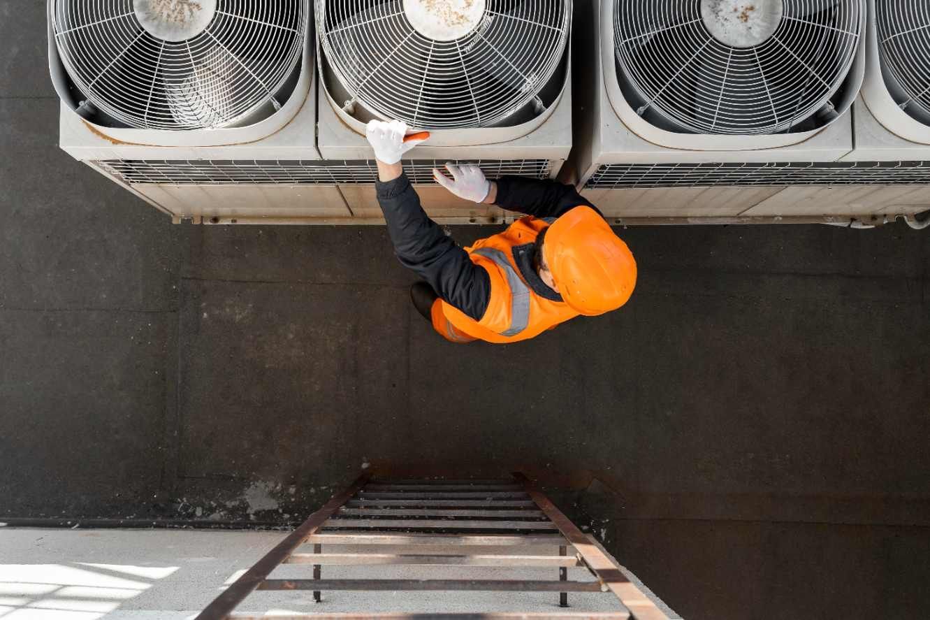 Technician inspecting an outdoor air conditioner unit beside a house with a wrench and gauges