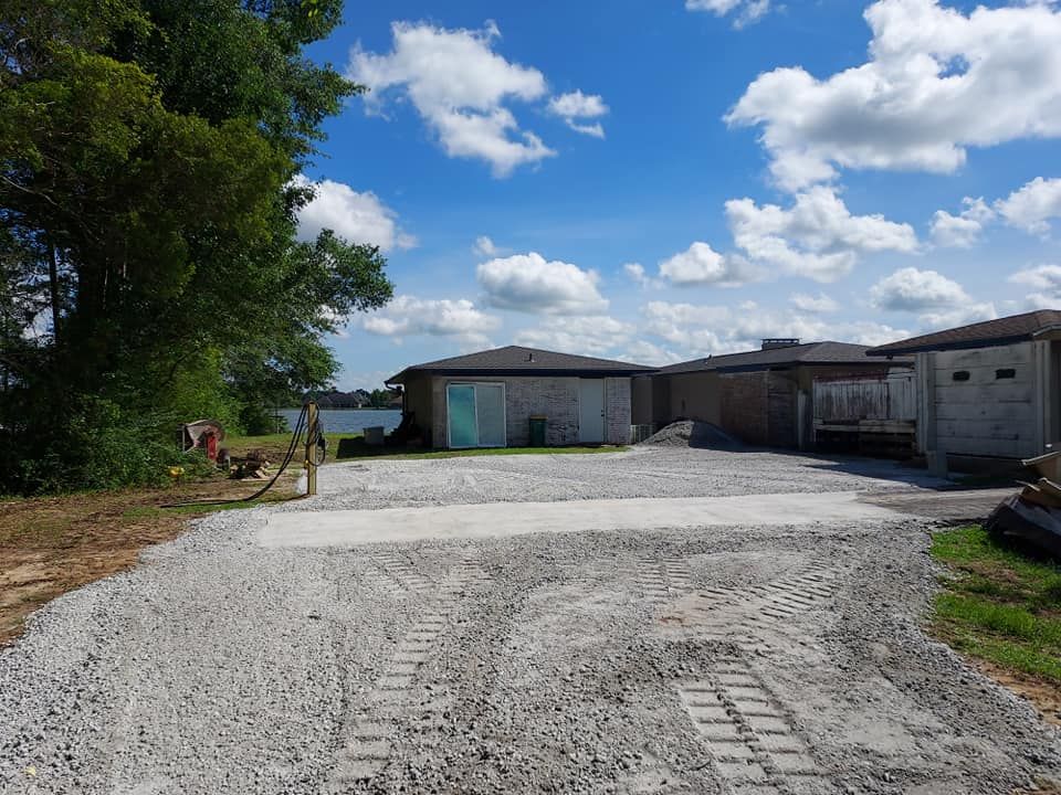 Gravel driveway leading to buildings under a bright blue sky with puffy white clouds.