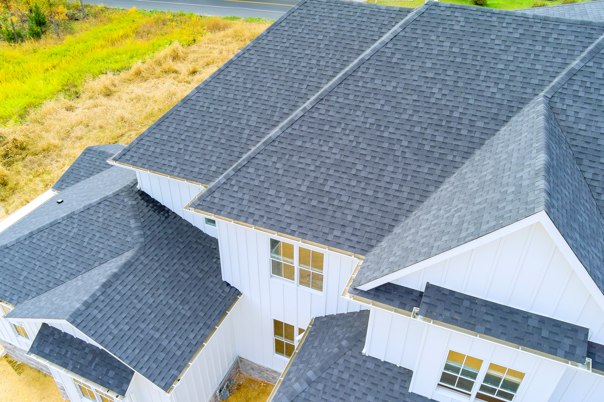 Aerial view of a white house with a dark gray shingle roof.