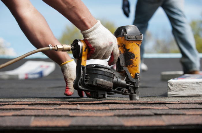 two men on top of roof putting down shingles