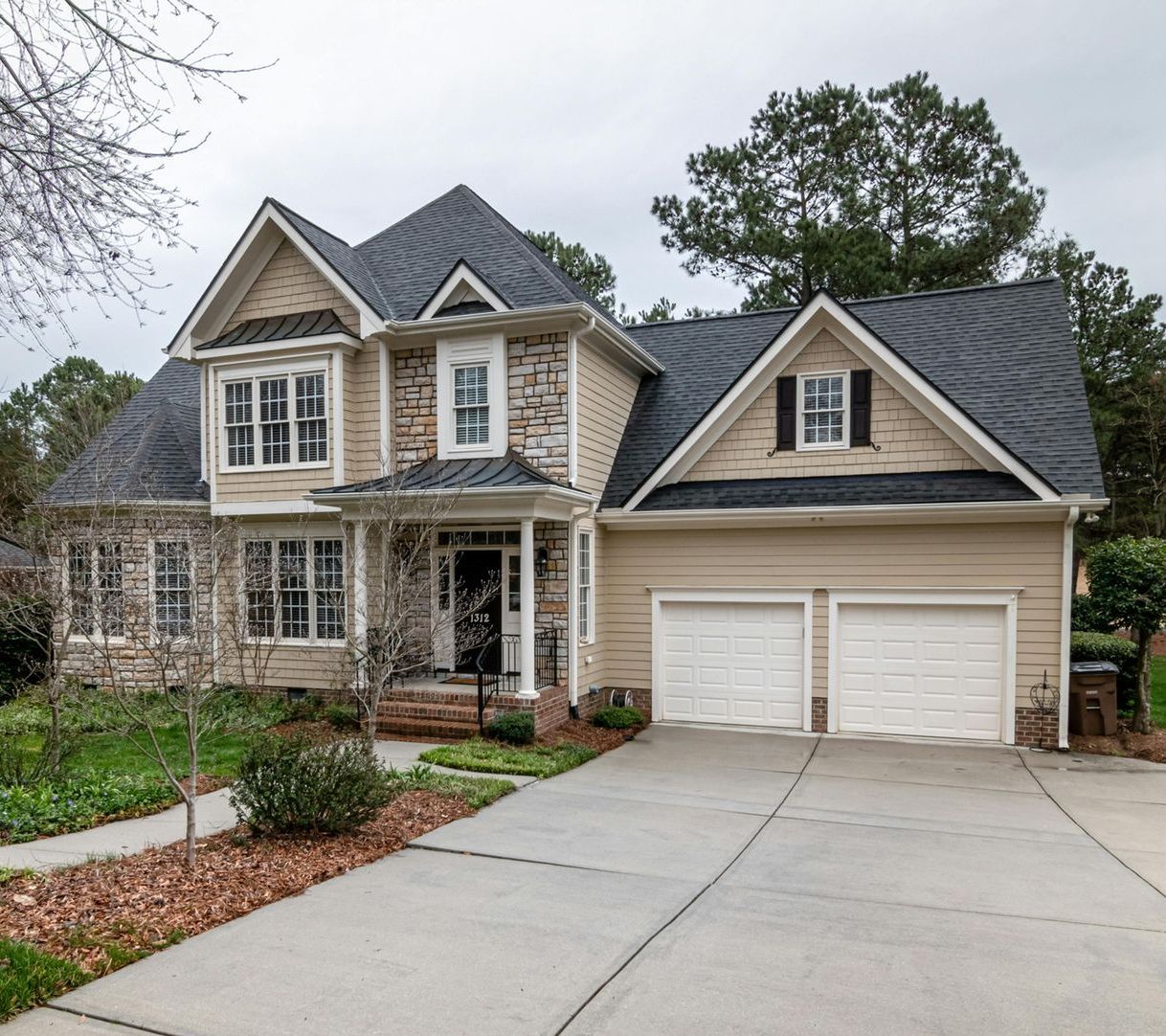 A large house with a gray roof and white garage doors
