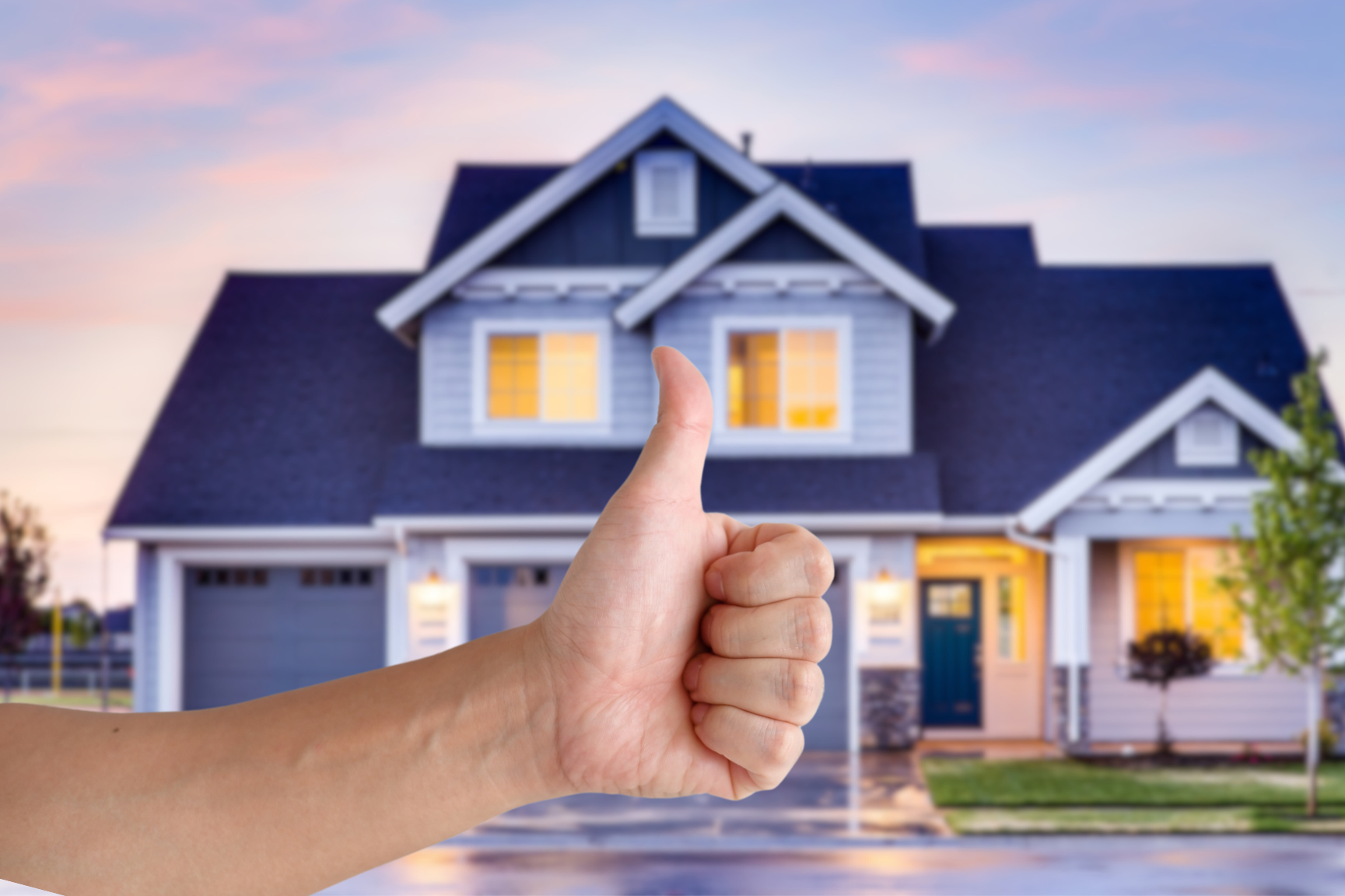 thumbs up with a blurry house in background