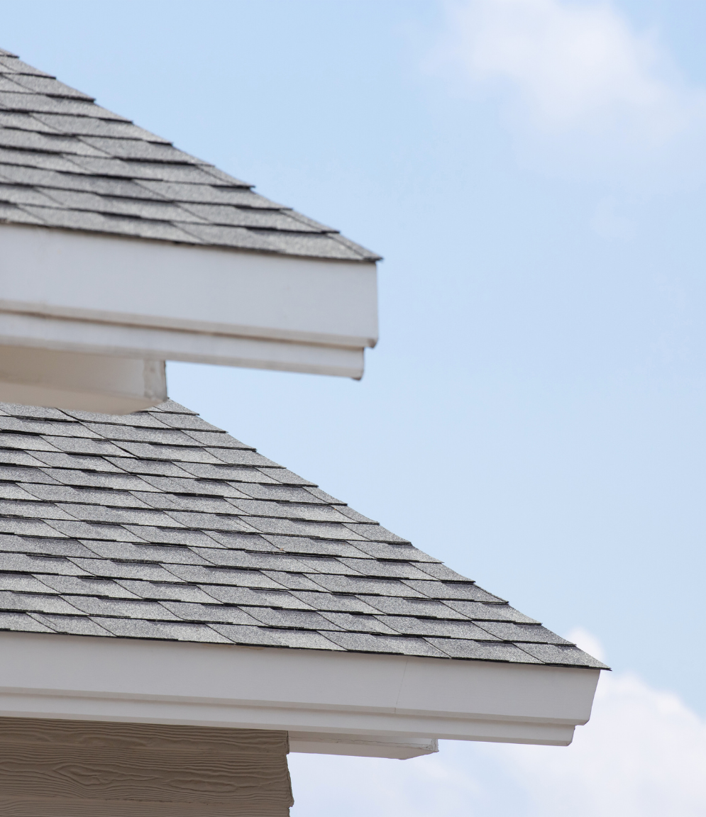 Corner of roof with asphalt shingles with blue skies behind